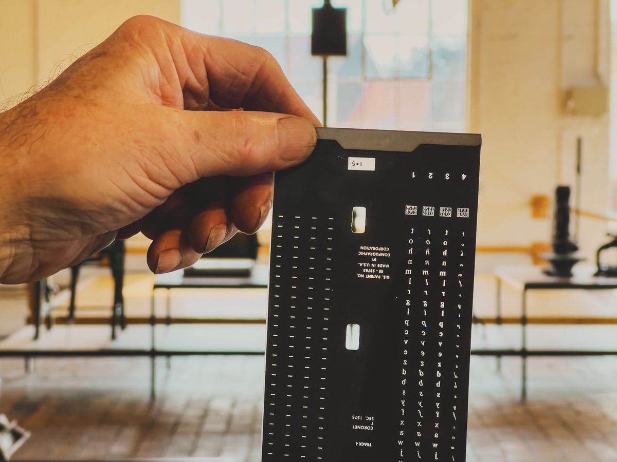 A hand holding the film version of the Coronet typeface from a Compugraphic EditWriter 7500 phototypesetter. Image Anthony Nelzin-Santos.
