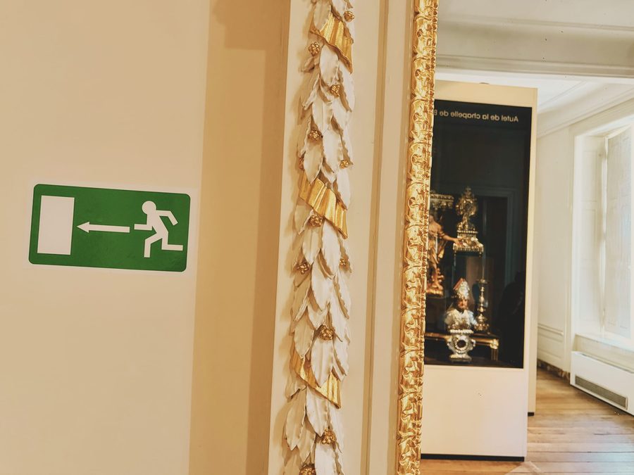 An exit sign juxtaposed with pieces of art in a museum.