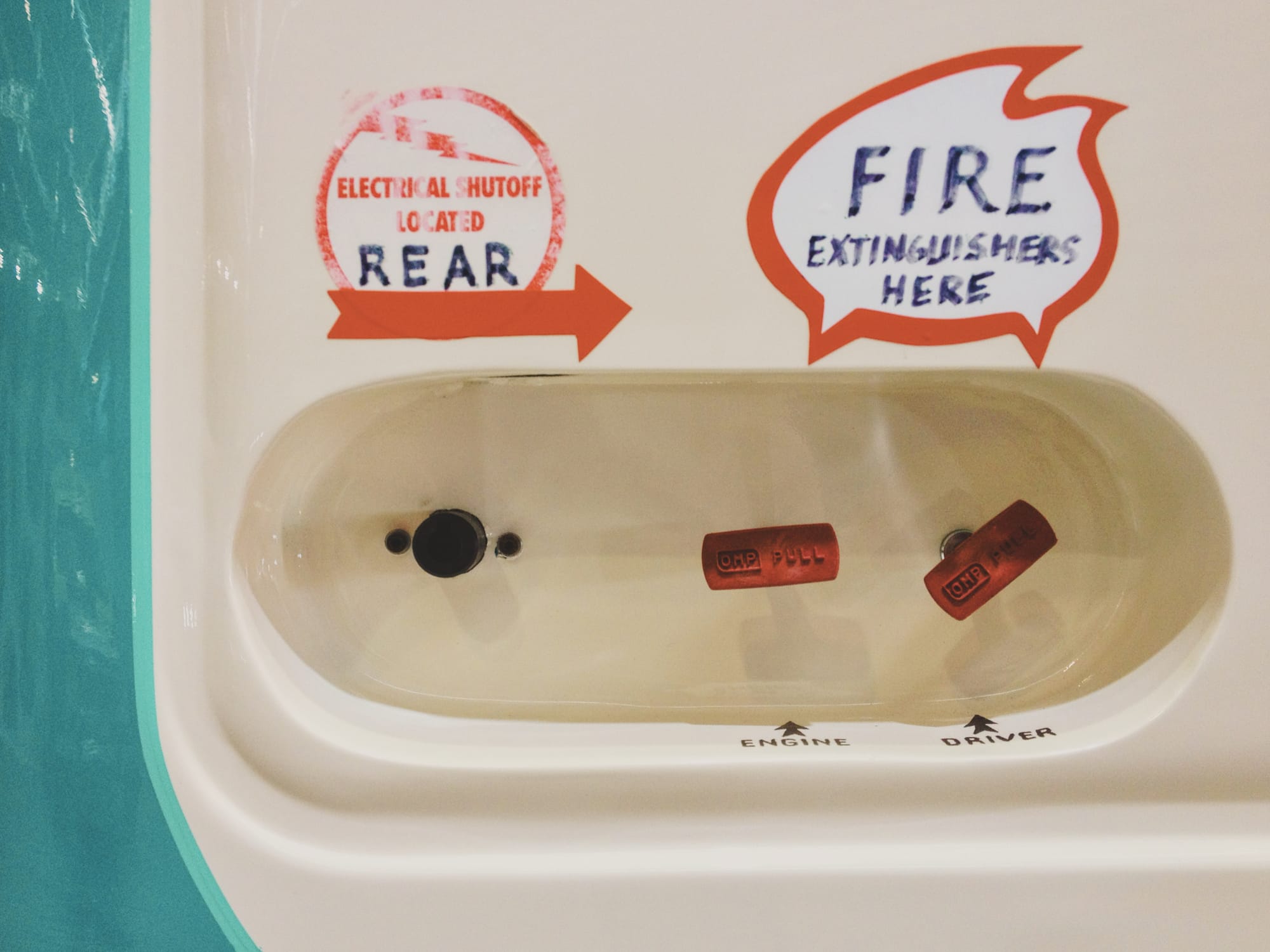 An electrical shutoff switch and two fire extinguisher handles on the side of an old truck.