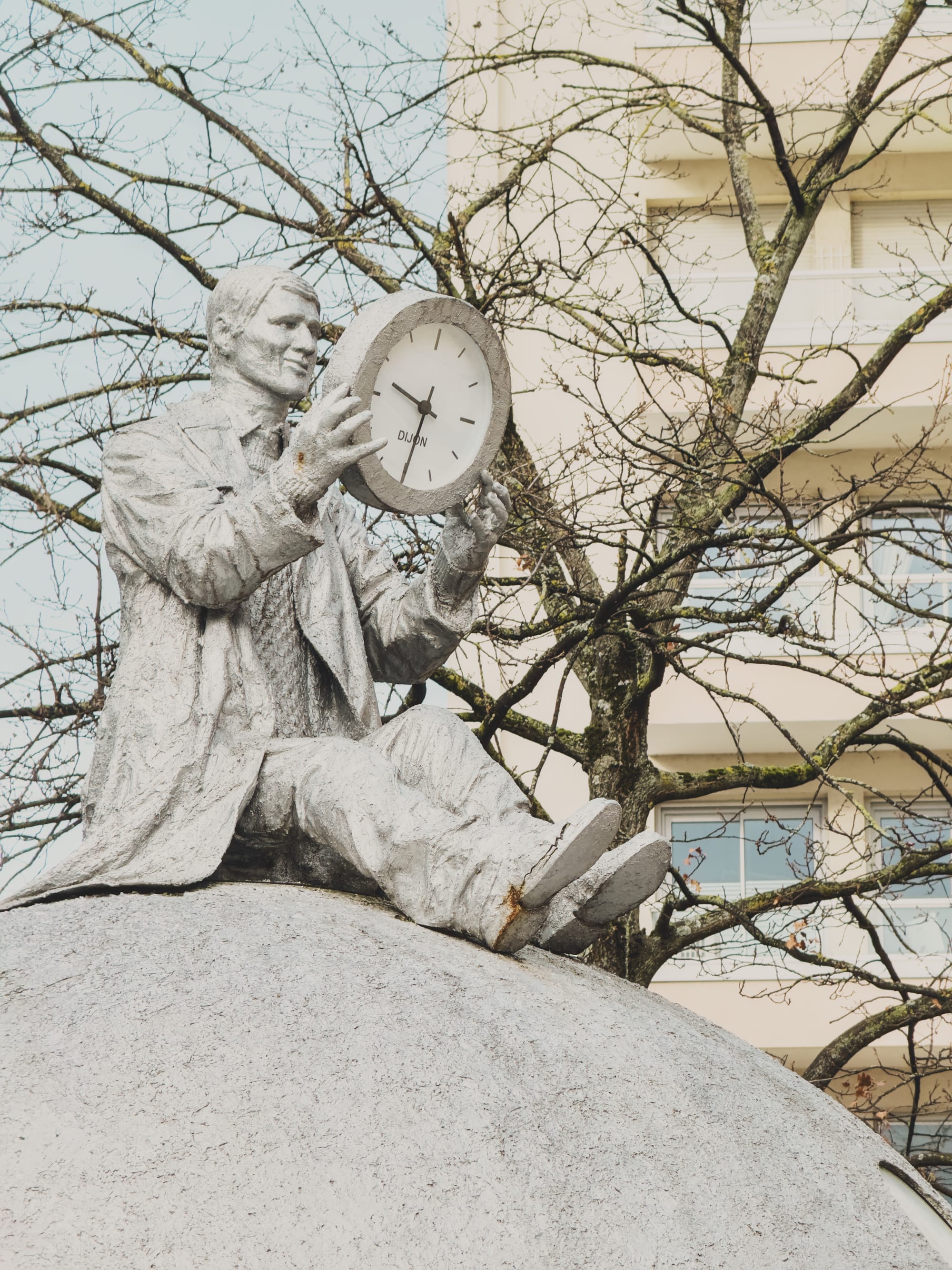 A statue of a man sitting on top of a sphere holding a clock. Image Anthony Nelzin-Santos.
