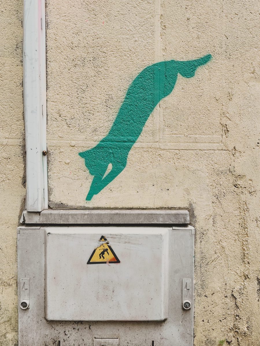 A mural of a green cat appearing to jump in an electrical junction box.