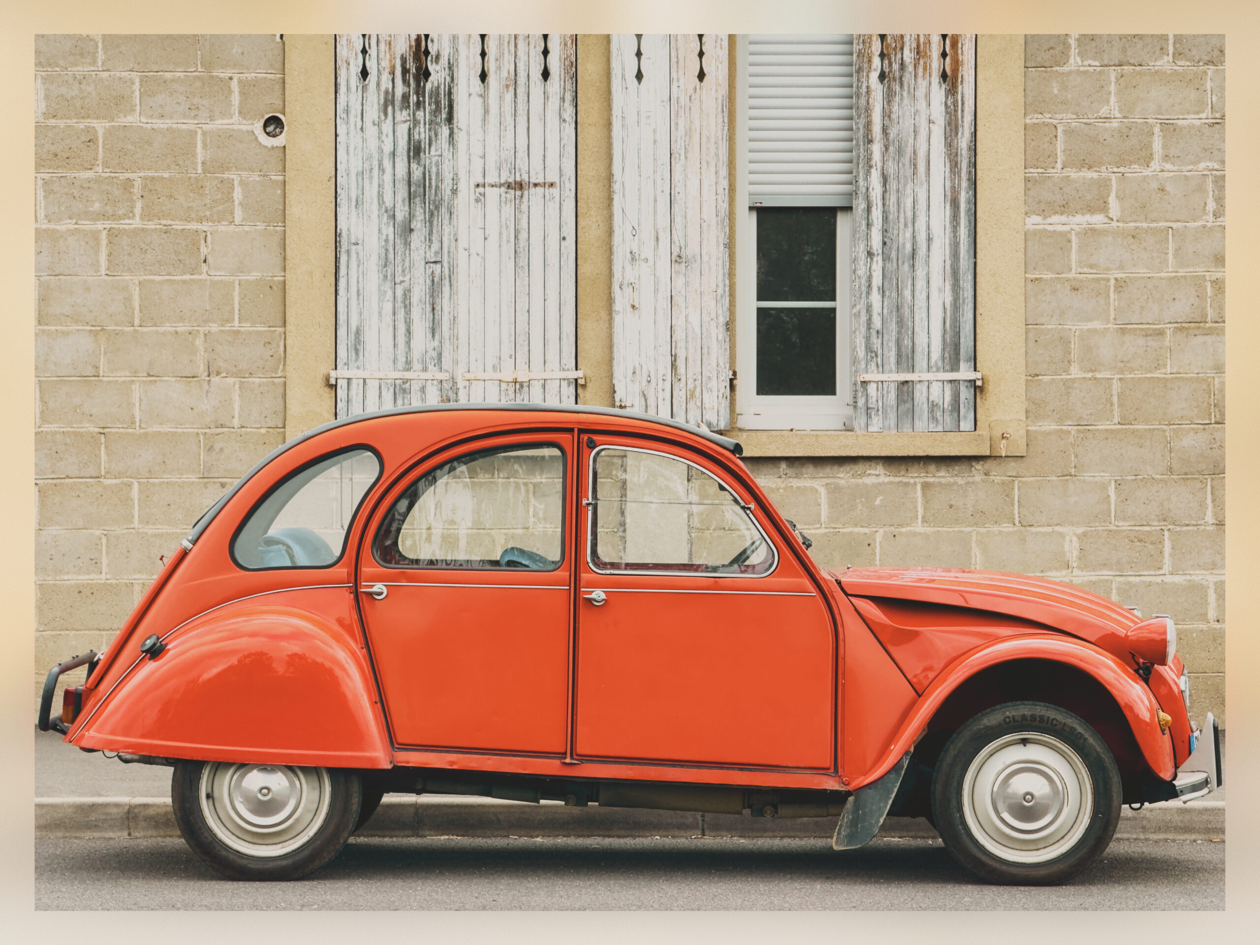 A Citroën 2CV in front of an old building.