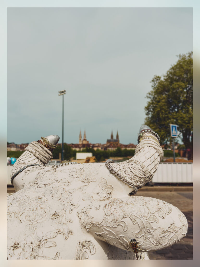A sculpture of a cow overlooking the church and the cathedral of Moulins.