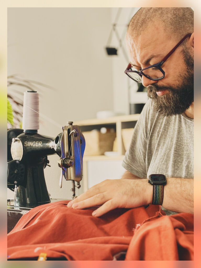 A man sewing on an old Singer sewing machine.