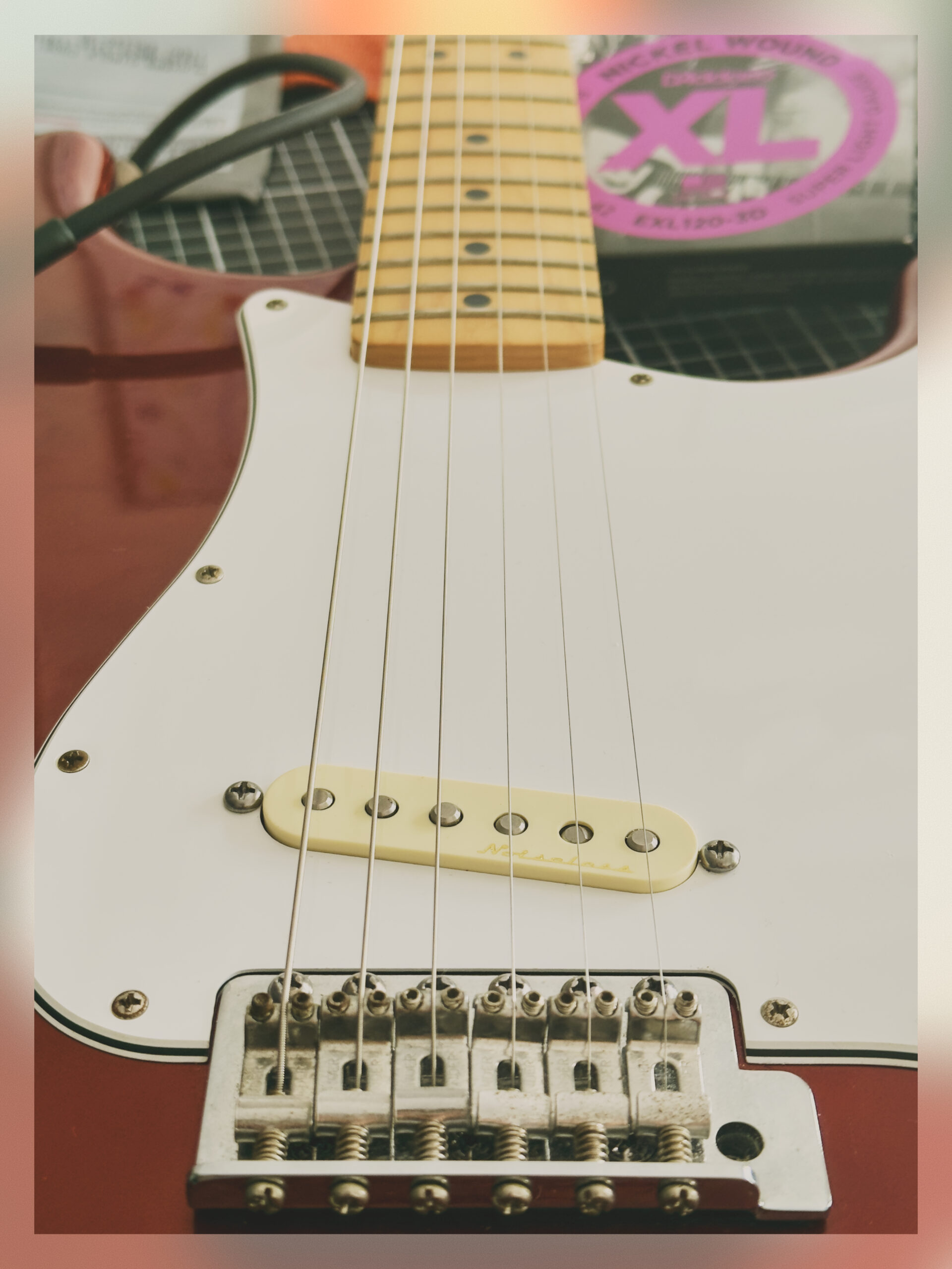 A picture of a red guitar with a single pickup.