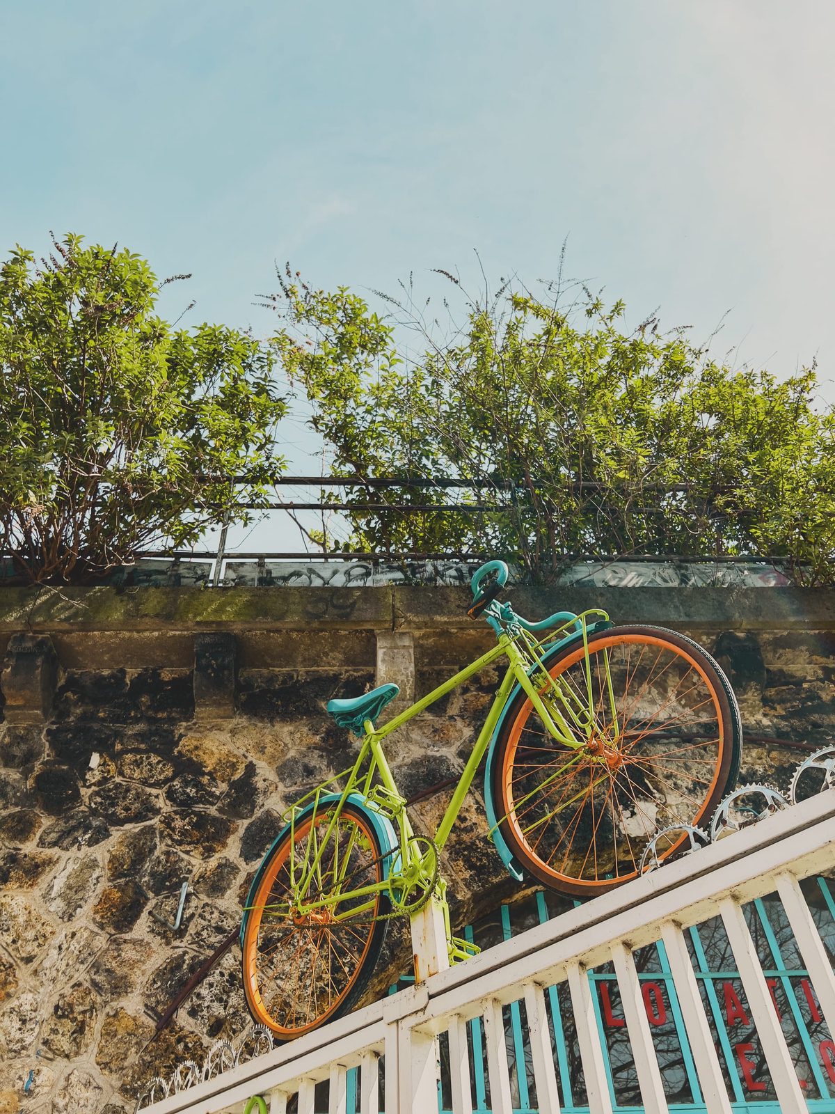 A multi-coloured bike hoisted on top of a bike shop’s entrance grid.
